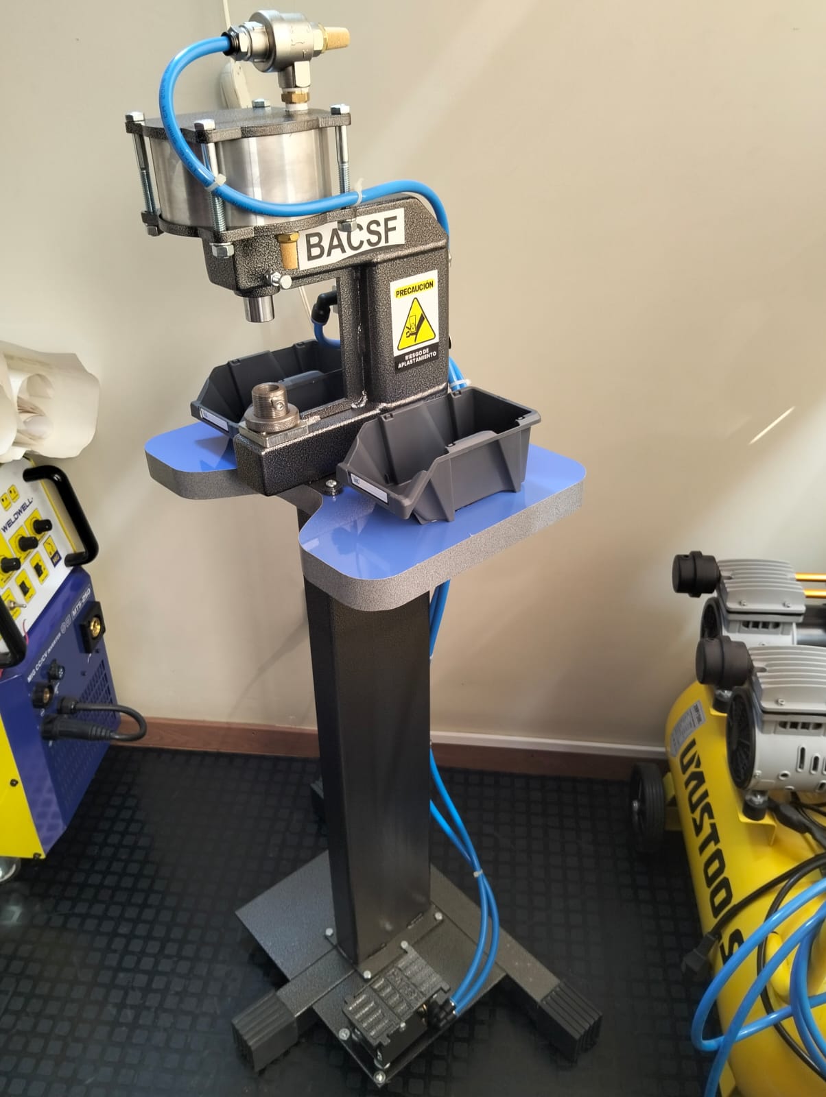Prensa neumática regulable BACSF en pedestal, vista lateral con compresor